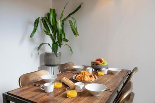 une table en bois avec des aliments pour le petit-déjeuner et une plante en pot dans l'établissement Loft Gramont  Cozy Studio - au calme - centre ville - tout à pied, à Biarritz