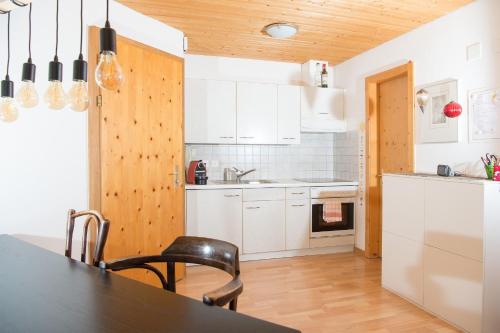 a kitchen with white cabinets and a black table at Zwei Zimmer Ferienwohnung Rabiusa Churwalden in Churwalden