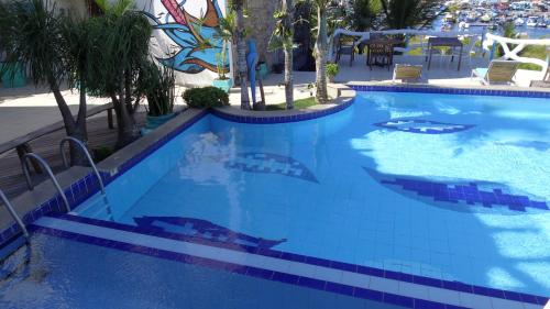 a large swimming pool with blue tile in a resort at Capitão N Areia Pousada in Arraial do Cabo