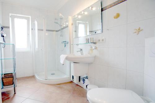 La salle de bains blanche est pourvue d'un lavabo et d'une douche. dans l'établissement Museumstra_e 16_ Whg_ 7, à Wyk auf Föhr