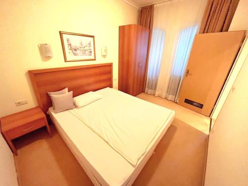 a bedroom with a large white bed with a wooden headboard at "Красавиците тъмнокоси" Sunset Resort Pomorie in Pomorie