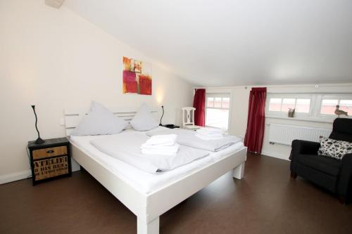 uma cama branca num quarto com um sofá e uma cadeira em Susanne-Fischer Weg 33, Haus Garnele em Wyk auf Föhr