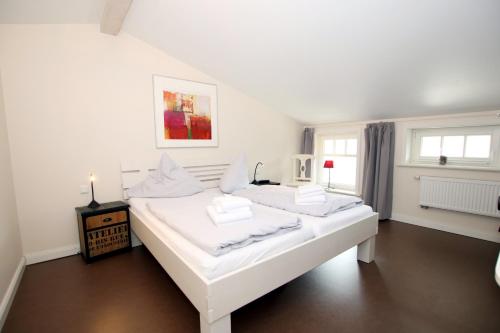 ein weißes Schlafzimmer mit 2 Betten und einem Fenster in der Unterkunft Susanne-Fischer Weg 37, Haus Einsiedlerkrebs in Wyk auf Föhr