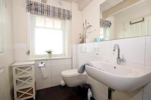 La salle de bains blanche est pourvue d'un lavabo et de toilettes. dans l'établissement Susanne-Fischer Weg 43, Haus Brandgans, à Wyk auf Föhr