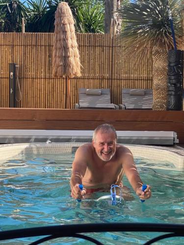 a man in a swimming pool with two water glasses at Little Bohême, luxe, piscine, SPA, tout à pied, Port Grimaud in Grimaud