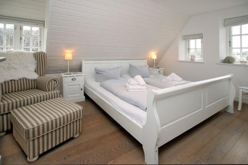 a white bedroom with a bed and a chair at Ohl Doerp 55b_ Whg_ 2 in Wrixum