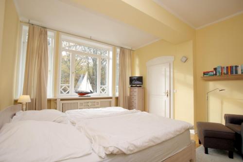 - une chambre avec un grand lit blanc et une fenêtre dans l'établissement Gmelinstra_e 22_ Whg_ 3_ Haus Frie, à Wyk auf Föhr