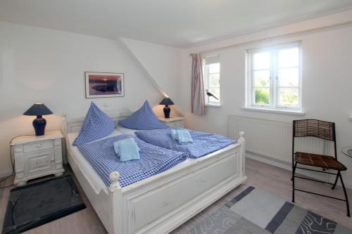 un letto bianco con cuscini blu in una camera da letto di Karkstieg 6_ Whg_ 2_ Vogtum a Wrixum