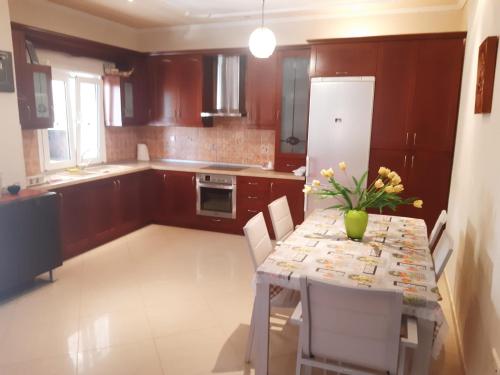 a kitchen with a table with a vase of flowers on it at Holly George Villa in Nea Plagia