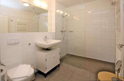 ein weißes Bad mit einem Waschbecken und einem WC in der Unterkunft Strandstraße 18b, Whg. 1, Haus Paula in Wyk auf Föhr
