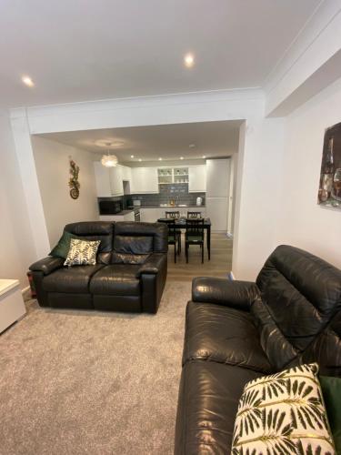 a living room with a leather couch and a table at Modern 2 bedroom apartment, with car parking. in Oldland Common