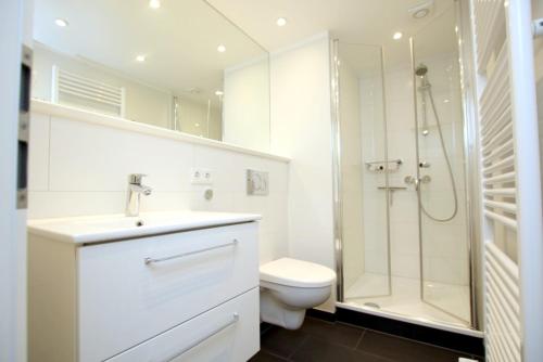 a white bathroom with a toilet and a shower at Ohl Doerp 22 Pastoratshof_ Haus 6 in Wrixum