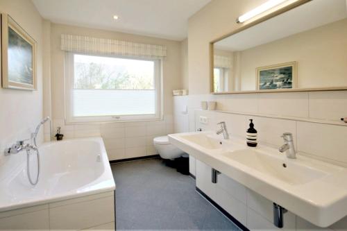 a bathroom with two sinks and a tub and a toilet at Linge 4_ Whg_ 1_ Hygge in Wrixum