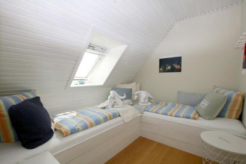 a attic room with two beds and a window at Linge 4_ Whg_ 2_ Nordliv in Wrixum