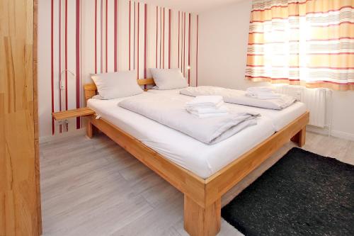 ein Bett mit weißer Bettwäsche und Handtüchern darauf in der Unterkunft Kiek Ut 9, Whg. 3 in Wyk auf Föhr