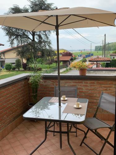 un tavolo e sedie sotto un ombrellone su un patio di Colline Di Barengo Apartment a Momo