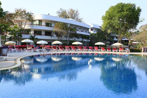 a swimming pool with chairs and umbrellas in front of a hotel at Novotel Rayong Rim Pae Resort in Klaeng