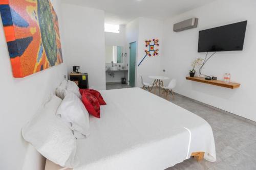 um quarto com uma cama branca e uma televisão de ecrã plano em Hotel Lucero Chan em Santa María del Oro