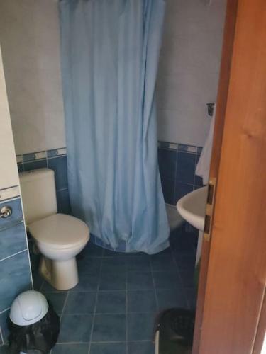 a bathroom with a toilet and a sink with a blue shower curtain at Sirena condo 50 m from the central beach in Byala