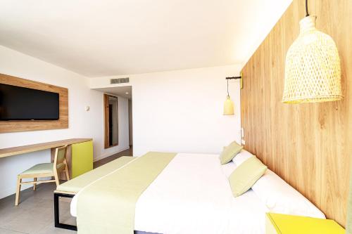 a hotel room with a bed and a desk at Ibersol Siurell in Sa Coma