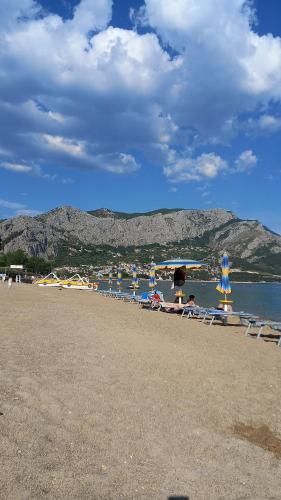 einen Strand mit Liegen und Sonnenschirmen auf dem Wasser in der Unterkunft Bugenvilija in Duće