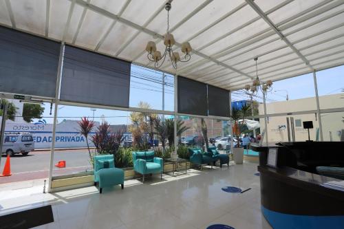 a lobby with blue chairs and a grand piano at Hotel Maresta Lodge - Hotel Asociado Casa Andina in Chimbote