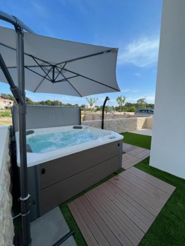 a hot tub with an umbrella on a patio at Black Pearl in Novalja