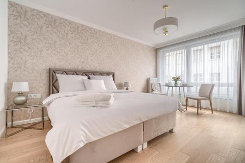 een witte slaapkamer met een groot bed en een tafel bij APARTAMENT STARE MIASTO UL. WIELKA ODRZAŃSKA SZCZECIN in Szczecin