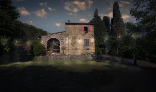 a stone building with a red window on top of a pond at Casa nel bosco Il Grottone in Montaione