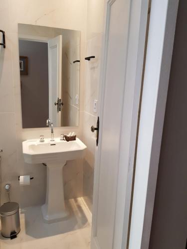 a white bathroom with a sink and a mirror at Pousada Orquidea da Serra in Petrópolis