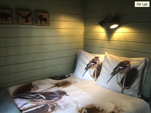ein Bett mit Vögeln auf den Kissen in einem Zimmer in der Unterkunft B&B De Flecht - De Ljip in Nijega