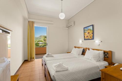 a bedroom with two beds and a large window at Lefktron Hotel in Stoupa