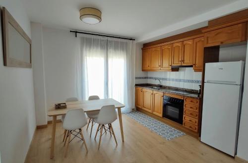 a kitchen with a table and chairs and a white refrigerator at Aixopluc - Apartamento centro rio Ritort in Camprodon
