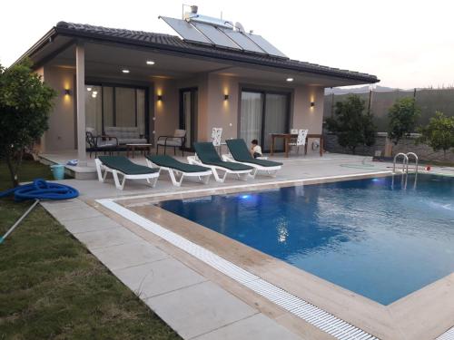 a swimming pool with chairs and a house at Villa Ayla in Fethiye