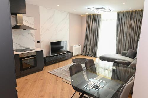a living room with a glass table and a kitchen at White Hill Hotel, SPA & Conferences in Durrës