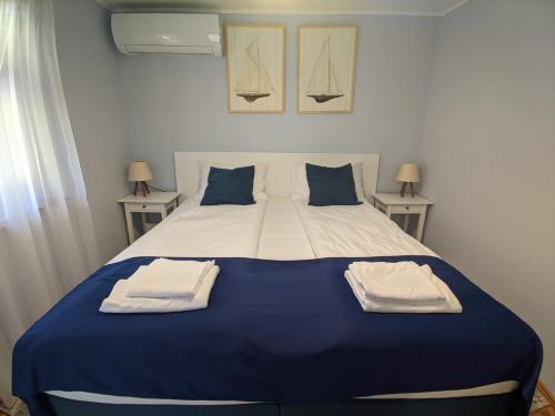 巴拉頓菲茲弗的住宿－Blue Haven Vendégház, Balatonfűzfő，卧室配有蓝色和白色的床和两张桌子