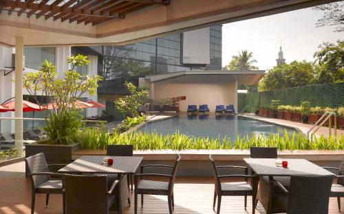 un patio esterno con tavoli, sedie e piscina di Gran Melia Jakarta a Giacarta