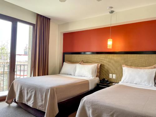 a hotel room with two beds and a window at Hotel Catedral in Mexico City