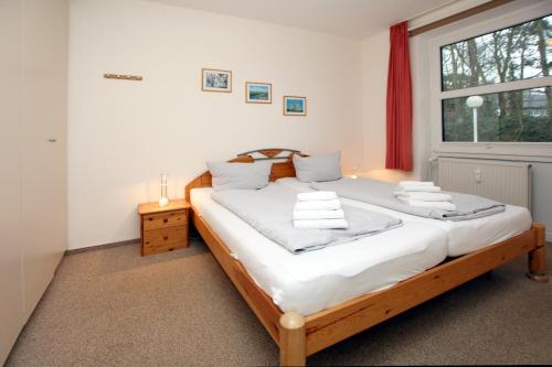 een slaapkamer met een bed met witte lakens en een raam bij Waldstraße 19a, Whg 21, Feriendomizil am Südstrand in Wyk auf Föhr