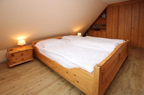 a large wooden bed in a room with two lamps at Ohl Dörp 22 Pastoratshof, Haus 5 in Wrixum