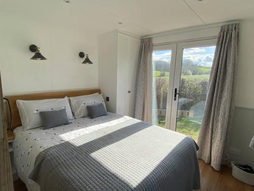 a bedroom with a bed and a large window at The Hoppers' Halt in Staplehurst