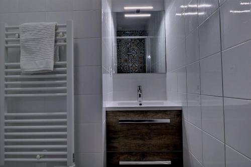 une salle de bain blanche avec un lavabo et un miroir dans l'établissement Appartement "PANNA" centre ville de VITRÉ, à Vitré