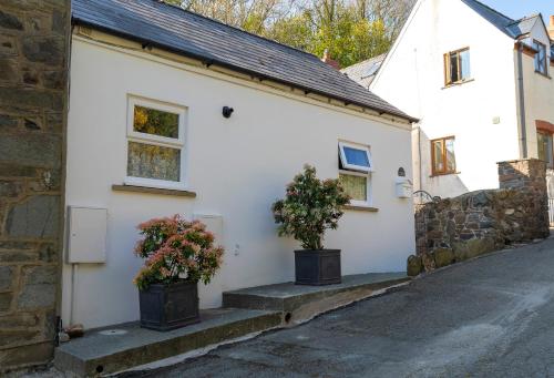 a white house with two potted plants on the steps at Rosebud cottage Romantic cottage for a couple in Fishguard