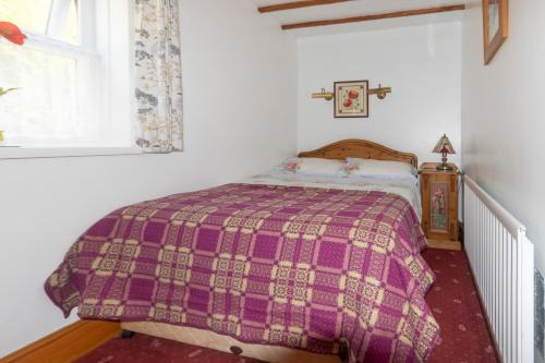 1 dormitorio con 1 cama con manta morada en Rosebud cottage Romantic cottage for a couple en Fishguard