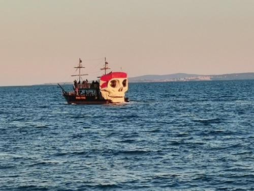 a pirate ship with a skull on it in the ocean at "Красавиците тъмнокоси" Sunset Resort Pomorie in Pomorie