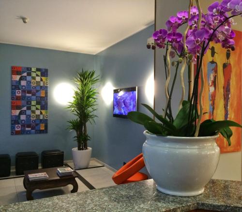 a white vase with purple flowers on a counter at Hotel Arcobaleno in Vimodrone