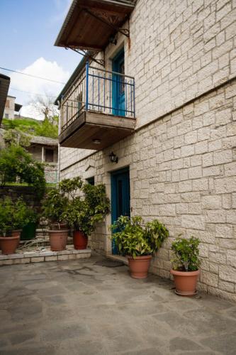 a building with a balcony and potted plants on it at Napoleon Zaglis Guesthouse in Kalarrites