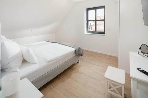 a white bedroom with a bed and a window at Küsten Suite West seitliche Wasserlage, 1 Balkon, 90qm in Greetsiel