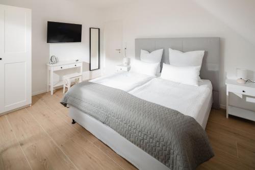 1 dormitorio con 1 cama blanca grande y TV en Küsten Suite West seitliche Wasserlage, 1 Balkon, 90qm, en Greetsiel