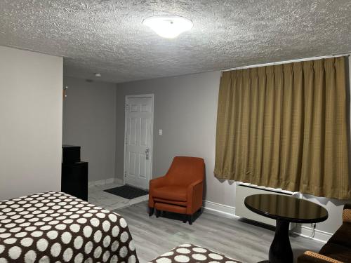 a bedroom with a bed and a chair and a table at Wiarton Willys Inn in Wiarton